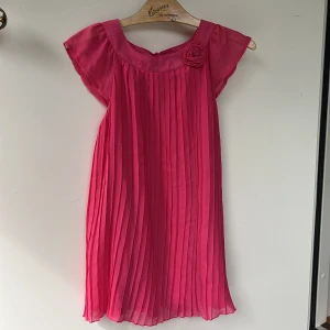 Cerise tunika och tights  - Ett set med en rosa tunika och ett par rosa tights med ett blommigt mönster. Tightsen är 3/4 längd och är tillverkade i ett mjukt och bekvämt material.