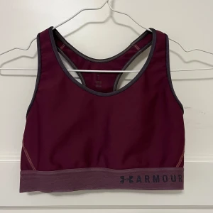 Under Armour sport-bh - Sportbehå från Under Armour i storlek M. Mörk vinröd färg och med hål i ryggen. 