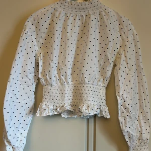 Vit och svartprickig blus - Säljer denna fina vita topp med svarta prickar då den inte används. Den är använd ett fåtal gånger och är i väldigt bra skick.  Bara att skriva om du vill ha fler bilder eller undrar över något.   (köparen står för frakten)