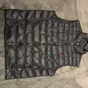 The Colden Packable Water-Repellent Gilet väst. Den isolerande fyllningen som används i denna vattenavvisande jacka är gjord av återvunnen polyester.  Två framfickor med dragkedja. Har använt den sammanlagt 2 månader och det är inga skador på den.