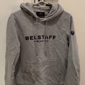 Belstaff Hoodie - En snygg grå märkes hoodie som är bekväm men jag har tyvärr vuxit ur den. Märket Belstaff, nypriset ligger på 1000kr+ där någonstans. Fint skick Storlek Small.