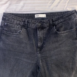Zara Straight Fit Jeans I Mörkgrå, Storlek 42 (US10) - Zara Straight Fit låg midja Jeans i färgen Mörkgrå. Normal fit med kedja. Storlek 42, passar till folk med storlek M i byxor. Jag är 163cm lång. Använd några gånger. Sitter lösare vid midjan än vanligt.