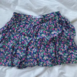 Så söt kjol med blommor och volanger! Perfekt till sommaren. Den är rätt så kort i modellen men har insydda shorts!! 