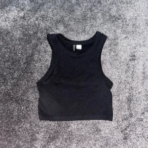 Svart Ribbat Linne - Ribbat linne från H&M. Väl använd men i bra skick. Lite cropped och har en fin passform på mig, (S). 