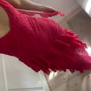 En superfin mörkrosa-röd klänning från zara i storlek S. Har en liten volang slinga hängandes vid sidan. Aldrig använd!