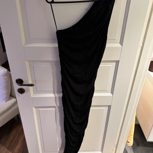 Svart rynkad klänning - Aldrig använd. Asymmetrisk samt one-shoulder.