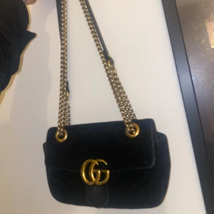 Gucci väska  - Säljer min fina Gucci väska jag fick i present år 2019. Inte använd jätte mycket så är bra skick dock lite repor från kedjan därav priset. Hittade lite info om väskan som jag lagt ut som sista bild. Väskan är äkta och är köpt på Gucci butiken i sthlm