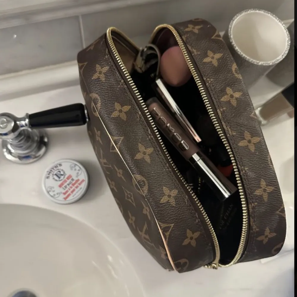 Detta Louis Vuitton toalettartiklar/sminkfodral är idealiskt för att hålla saker organiserade på ett lyxigt sätt. Kan användas som handhållen clutch, necessär, sminkväska eller en mindre väska att ha i en mindre väska. . Väskor.