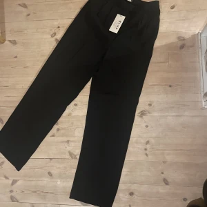 Kostymbyxor  - Svarta kostymbyxor som svänger ut vid benen (aldrig använda)