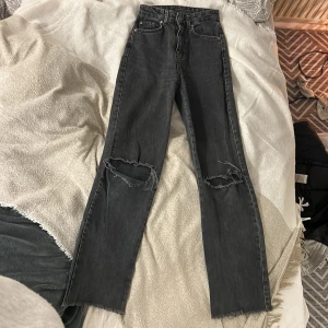 Stradivarius Svarta jeans med hål - Ett par straight svarta jeans med hål på knä och lite fransigt nertill från stradivarius. Skit snygga men säljer då jag tyvärr inte använder dom längre. De har slitits lite mellan benen men det är inget som syns. Stl.32