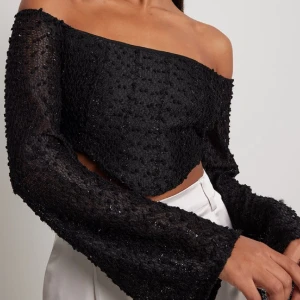 Svart glittrig topp från NA-KD - Säljer denna oanvända svarta glittriga topp från NA-KD då jag beställde en för liten storlek och det är för sent för att skicka tillbaka den💞 prislappen är kvar🫶🏼  Postar gärna om köparen betalar frakten💌💸