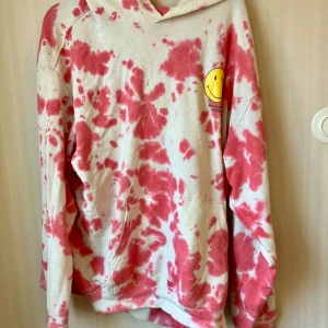 Färgglad hoodie - En riktigt skön & go hoodie som lyser upp både dig själv och omgivningen! Med dessa vitrosa mönster och gula glada smileys så lär du mötas av många glada miner! 