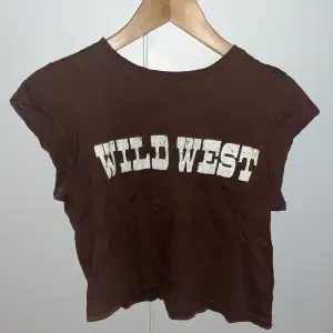 Brun tröja med halv armar mellan linne och t shirt, med texten ”wild west” från HM.