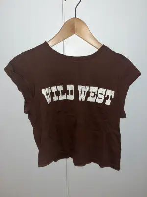 Brun tröja med halv armar mellan linne och t shirt, med texten ”wild west” från HM.