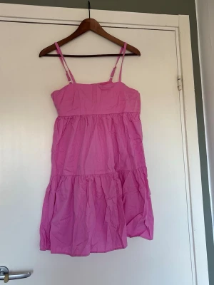 Rosa sommarklänning med tunna axelband - Söt rosa kortklänning med tunna axelband och volangig kjol. 