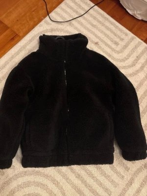 Svart teddyjacka från Noless Relish - Mysig svart teddyjacka från Noless Relish i storlek S. Jackan har hög krage, dragkedja framtill och två fickor. Sällan använd och väldigt gott skick💞