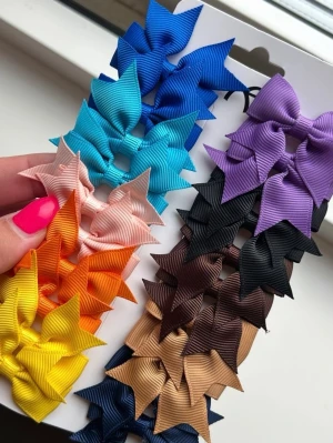Färgglada hårspännen med rosetter - Säljer ett set med 20  hårspännen i metall dekorerade med ribbade rosetter i olika färger som blå, turkos, lila, svart, beige, brun, orange, gul och rosa. Perfekta för att piffa upp frisyren och matcha med olika outfits. Rosetterna har en klassisk form och sitter stadigt på spännena.