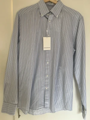 Skjorta These Glory Days - Klassisk blårandig skjorta från These Glory Days. Helt sprillans, aldrig använd (etikett kvar se bild). Passar till det mesta, perfekt nu inför våren. Hör av er vid frågor! Passar någon kring 180 cm 70kg. 