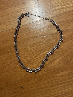Kedjehalsband i silverfärgad metall - Stilrent halsband i silverfärgad metall med grova länkar som ger en edgy känsla. Justerbar längd med förlängningskedja och karbinlås. Perfekt för att lyfta din outfit med en cool detalj.