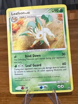 Pokemon Leafeon Pokémonkort holografiskt - Säljer ett holografiskt Leafeon-kort från Pokémon, nivå 42 med 90 HP. Kortet har grön och gul ram, och motivet visar Leafeon mot en glittrande bakgrund. Kortet är från 2008 och har attackerna Bind Down och Leaf Guard. Perfekt för samlare eller Pokémonfans!