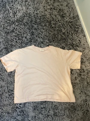 Ljusrosa basic t-shirt - En enkel och stilren ljusrosa t-shirt med rund hals och korta ärmar. Perfekt till jeans eller shorts för en avslappnad look.