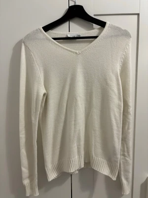 Vit stickad tröja från Vila - Klassisk vit stickad tröja från Vila med v-ringning och långa ärmar. Tröjan har ribbstickade muddar vid ärmslut och nederkant. Enkel och stilren design som passar till mycket. Materialet känns mjukt och bekvämt. Använd fåtal gånger. Säljer eftersom den inte kommer till användning. Skriv gärna innan ni köper ❤️