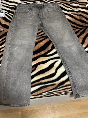 Grå raka jeans från 157 - Säljer ett par grå jeans från 157 med rak passform och klassisk femficksdesign. Jeansen har en tvättad look och är tillverkade i denim, perfekta för en avslappnad och trendig stil. Width: 36 lenght: 32