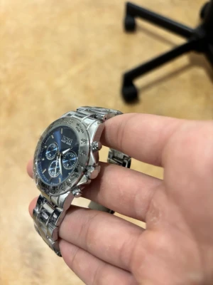 Hugo Boss silverfärgad klocka - Stilren klocka från Hugo Boss med blå urtavla och silverfärgat armband i metall. Klockan har tre mindre urtavlor, tydliga markeringar och klassisk rund form. Perfekt accessoar för dig som gillar en clean och modern look.