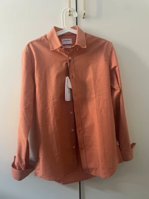 Orange skjorta från Lindbergh - Skit snygg skjorta med en riktigt snygg sommar färg, helt ny beställde i fel storlek darför jag säljer den 