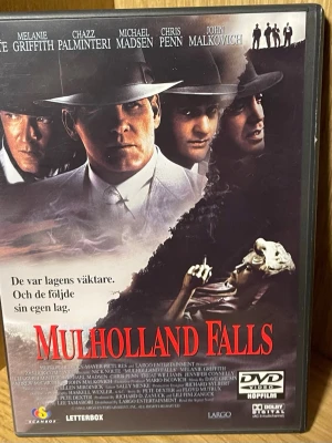 Mulholland Falls DVD-film - Säljer en DVD-film med titeln Mulholland Falls. Omslaget är svart med röda och vita detaljer, och har bilder från filmen samt information på svenska. Filmen är en action/thriller och utspelar sig i Los Angeles 1954. DVD-format med Dolby Digital.
