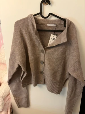 Beige kofta från 157 - Säljer en beige  kofta från Lager 157 med stora knappar framtill och ribbade muddar. Koftan här aldrig använd och har lappen kvar. Nypris: 150kr💞