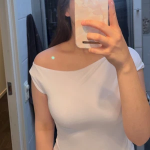 Vit offshoulder topp - Säljer en stilren vit offshoulder topp med en elegant passform. Perfekt för att skapa en chic look. Toppen är ärmlös och har en mjuk och bekväm känsla. Den är från Nelly och har prislappen på