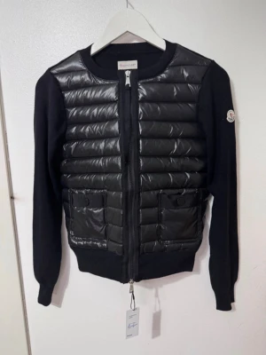 Moncler cardigan - Bought on Vinted, officially verified (authentic). In excellent condition - almost like new 99% Stylish hybrid design with padded front and knitted sleeves, super warm yet lightweight. Color: Black Size: S Veritied authentic by Vinted