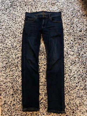 Lee jeans  - Snygga mörkblå jeans från Lee. Använda fåtal gånger. Strlk 30/34 men passar mer som 30/32. Mått, benlängd 104 cm midja 43 cm benöpningen 16 cm. Hör av dig vid minsta fundering! 