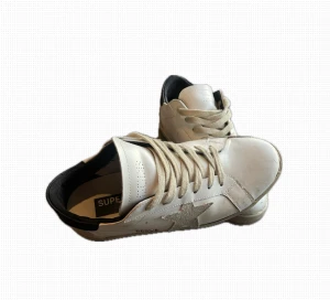 Golden goose - Golden Goose sneakers i vitt skinn med beige mockadetaljer och en stor stjärna på sidan. Skorna har snörning, svart häl och platt sula. Perfekt för dig som gillar en cool och avslappnad stil. Ikonisk design med kontrastfärgade detaljer. Obs sulan är limmad men funkar ändå och de är ett litet hål i under sulan som visas på bilden.