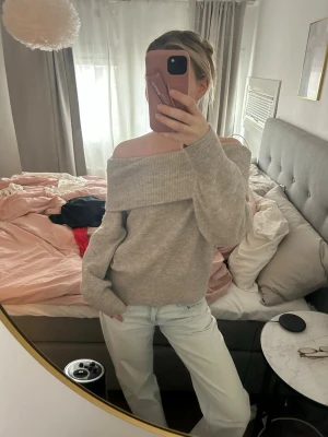 Beige off shoulder stickad tröja - Säljer en beige stickad tröja med bred off shoulder-krage. Tröjan har lång ärm och är gjord i ett mjukt material som känns skönt mot huden. Perfekt för dig som gillar en avslappnad och trendig look.