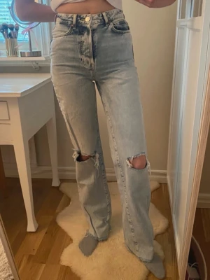 Ljusblå raka jeans med hål Bikbok - Säljer ett par ljusblå raka jeans med hög midja och slitna hål över knäna. Fina jeans från BikBok💙 Har används en del men säljer nu då dom inte kommer till användning längre🙌 Storlek 25, passar som en S.