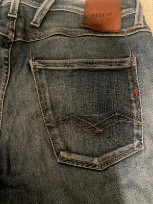 Blå Replay Hyperflex jeans - Snygga blå jeans från Replay Hyperflex med klassisk femficksdesign och feta väck bakom knäna samt feta slitningar. Längd 30 waist 27