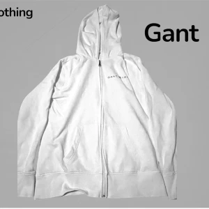 Vit hoodie med dragkedja från Gant - Snygg vit hoodie från Gant med dragkedja framtill och två fickor. Klassisk design med huva och diskret Gant-logga på bröstet. Perfekt för en avslappnad och stilren look. Mjuk insida för extra komfort.