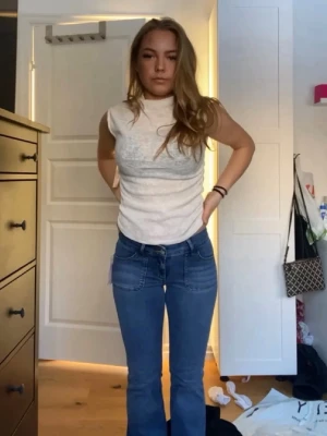 Vit ribbad ärmlös topp - Snygg vit ärmlös polotopp i ribbat material. Toppen har en hög hals och sitter tajt mot kroppen, perfekt att styla med både jeans och kjol. Enkle och stilren design som passar till många olika looks. Använd 1 gång 