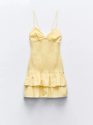 Gul kort klänning med volang - Söt gul kort klänning med tunna axelband och volang nertill. Klänningen har en smockad överdel och subtila ränder i tyget. Perfekt för varma dagar och ger en fräsch look. Materialet känns lätt och somrigt.