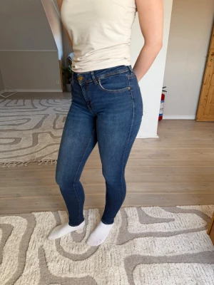 Mörkblå skinny jeans med hög midja - Snygga mörkblå skinny jeans med hög midja och klassiska fem fickor. Jeansen har en tight passform och stretchigt material som sitter bekvämt. Storlek M/32