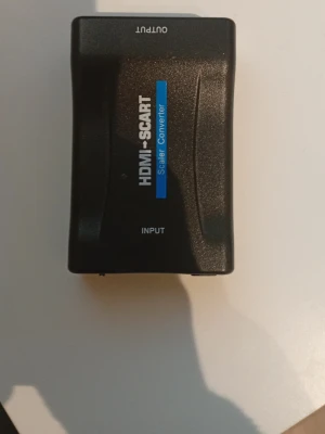 HDMI till SCART scaler converter - En svart HDMI till SCART scaler converter som gör det möjligt att koppla moderna HDMI-enheter till äldre SCART-utrustning. Har HDMI-ingång, SCART-utgång, PAL/NTSC-omkopplare och drivs med 5V DC. Perfekt för att ansluta nya konsoler eller mediaspelare till äldre TV-apparater.