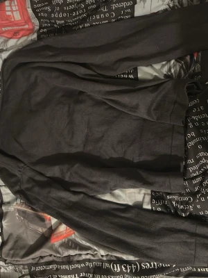 Mörkgrå långärmad tröja - En enkel och stilren mörkgrå långärmad tröja i mjukt material. Tröjan har rund halsringning och raka ärmar, perfekt för en avslappnad look. Passar bra till jeans eller över en skjorta för en mer uppklädd stil.