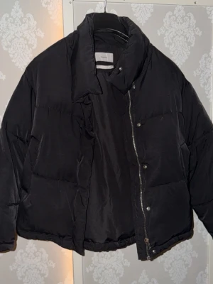 Svart pufferjacka från Bershka - Snygg svart pufferjacka från Bershka med hög krage och dragkedja samt tryckknappar framtill. Väldigt sparsamt använd och i mycket fint skick💕