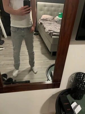 Ljusgrå slim fit jeans - Säljer ett par ljusblå slim fit/regular jeans med klassisk femficksdesign och dragkedjegylf. Jeansen har en snygg tvättad look och är tillverkade i mjukt denimtyg som sitter skönt. Perfekta till en avslappnad stil och passar till det mesta. Jeansen har ett litet hål vid skrevet men det går att sy ihop. Jag säljer byxorna för att de är för små och jag köpte dem för 900 kr för 6 månader sen. Längd 29/ Waist 32