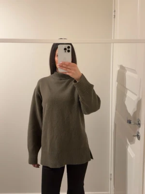 Olivgrön stickad polotröja - Säljer en olivgrön stickad polotröja med ribbade muddar och nederkant. Tröjan har en relaxed, loose passform och slitsar i sidorna för extra komfort. Perfekt för lager på lager och chill stil. Från h&m i storlek xs.