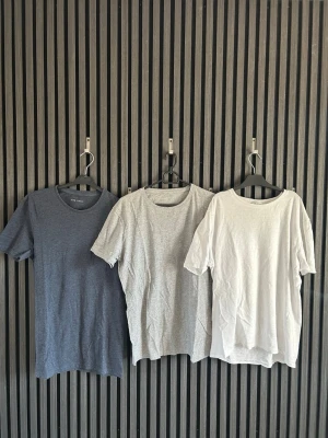 3-pack basic t-shirts i olika färger - Säljer ett 3-pack basic t-shirts i färgerna marinblå, grå och vit. Alla har rund halsringning och korta ärmar. Perfekta till vardags och enkla att matcha med allt. Tillverkade i mjuk bomull för skön känsla.