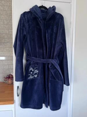 Mörkblå morgonrock från Bikbok, storlek S/M - Mysig och mjuk morgonrock från Bikbok med luva, långa ärmar och knytskärp i midjan. Broderad logga på ena fickan. Inte säker på storlek men skulle säga S/M. Fint skick!