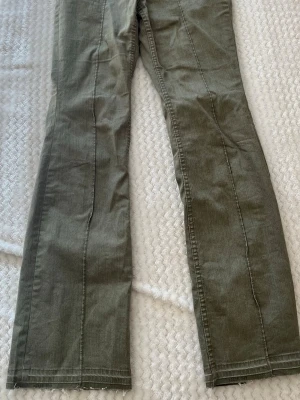 Olivgröna bootcut jeans - Snygga olivgröna jeans med bootcut passform och rå kant nertill. Jeansen har dekorativa sömmar framtill och är tillverkade i ett mjukt bomullsmaterial. Perfekta för dig som gillar en avslappnad men trendig stil.